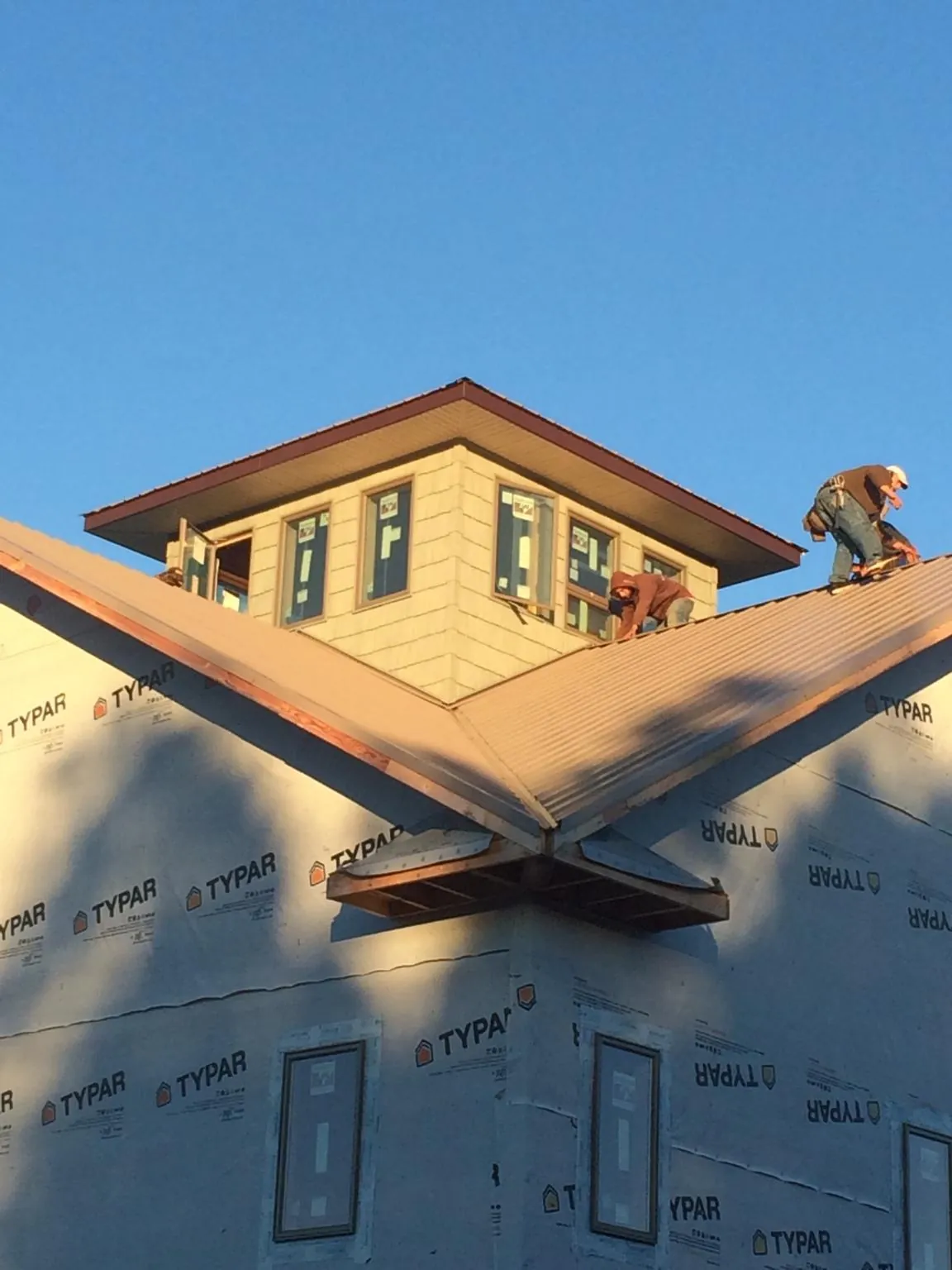 Roofers working around a rooftop cupola on a new metal roof at sunset — Roof Waterproofing in Jamestown by Roofing Brothers
